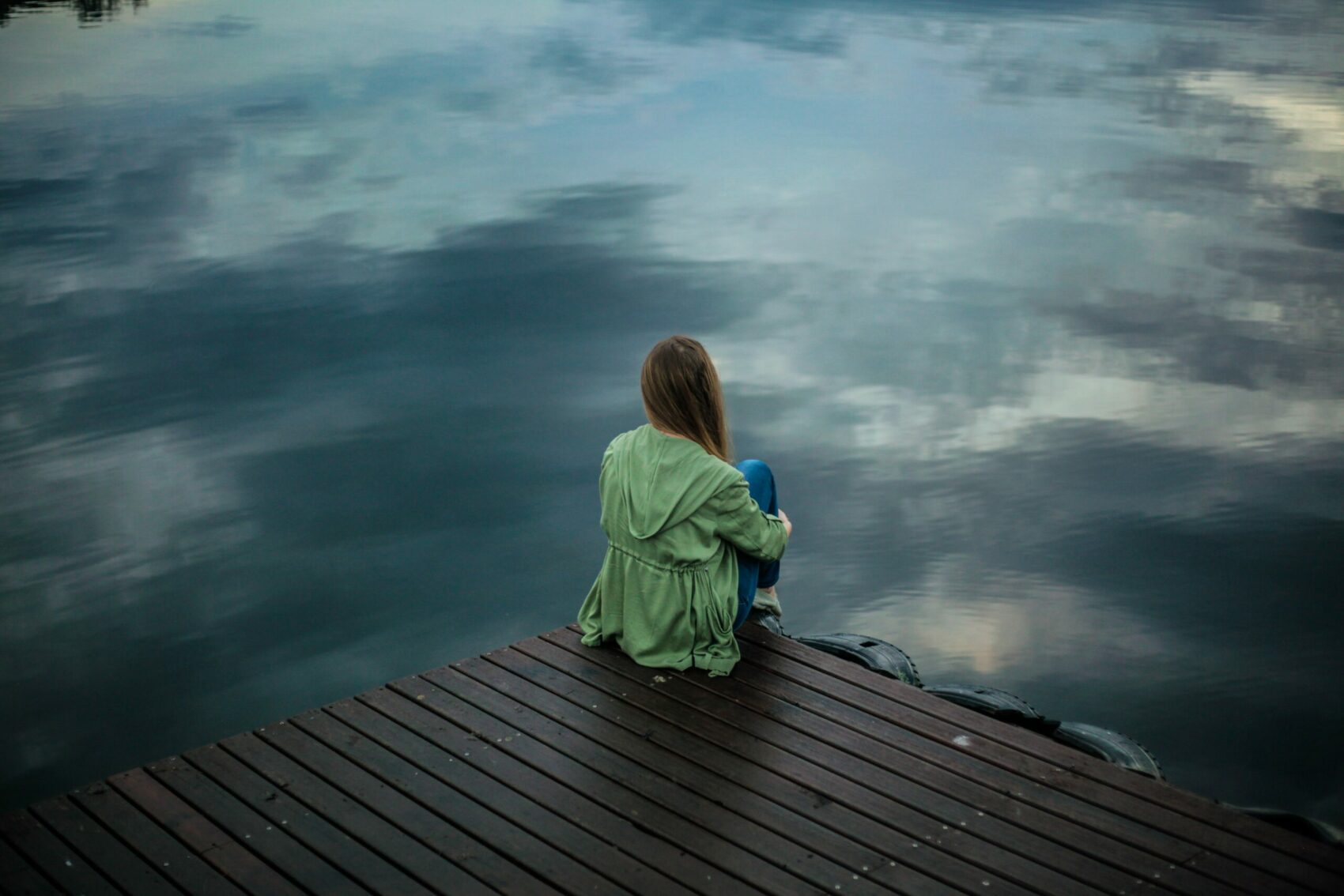 jeune fille assise devant un lac